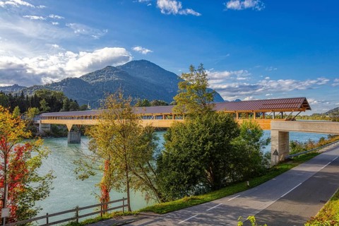 Landscape view of a wooden bridge over a river surrounded by autumnal nature and mountains, Inn