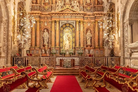 Opulent chapel with magnificent altar and elegant red benches, Seville