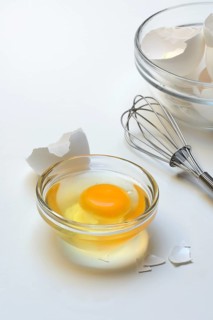 Egg whites and egg yolks in glass bowl and egg shells, whisk
