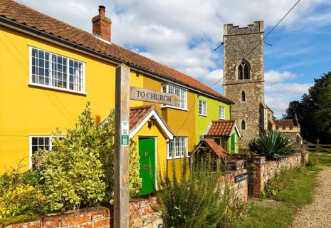 Historic cottages next to village parish church of All Saints, Rede, Suffolk, England, UK
