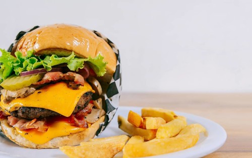 Homemade burger with french fries on a plate on wooden table. Big cheeseburger with fries served