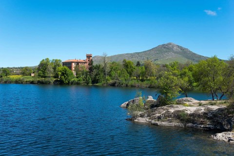Clear lake next to a building, surrounded by nature and mountains under a blue sky, palace, Palacio