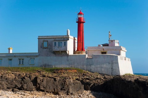 Close-up of a lighthouse on a rocky coast under a blue sky, Farol do Cabo Raso, São Brás de Sanxete