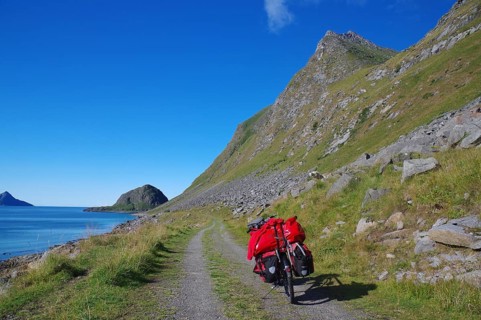 Cycling on a gravel road along the sea with a view of mountains and a bright blue sky, cycling