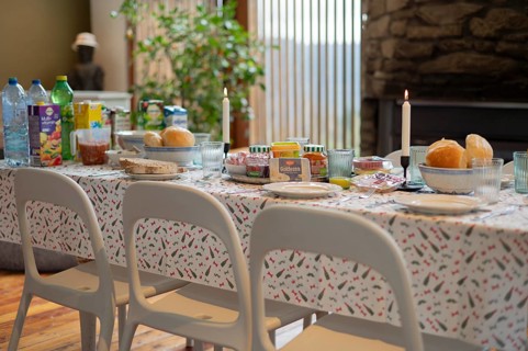 White table setting, plastic tablecloth, plates, cutlery, glasses, bread rolls, juice and spread,