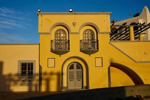 Yellow building with decorative balconies and large windows, illuminated by the last evening light,