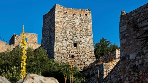 Medieval stone towers surrounded by Mediterranean vegetation under a blue sky, Lagia, residential