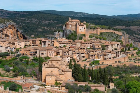 Medieval village with an impressive castle on a hill surrounded by green nature, collegiate church