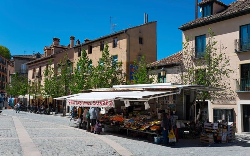 Sunny street scene with market stall, buildings and people in a town, Plaza de los Dolores, San