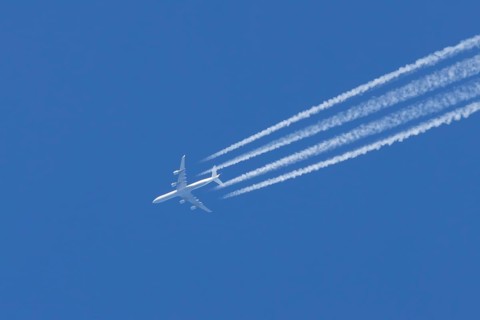 Airbus A340 aircraft flying across a blue sky leaving a contrail or vapor trail in the atmosphere