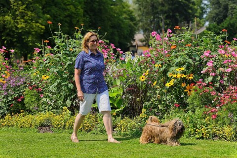 Woman takes Lhasa Apso for a walk in the park