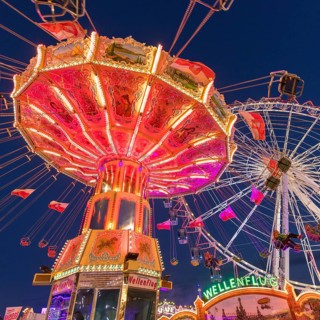 A funfair at dusk with illuminated chain carousel and Ferris wheel, Europa Rad, rides, wave flight,