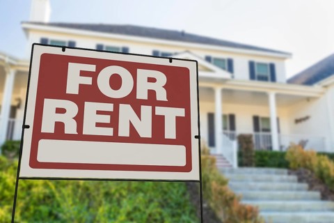 For rent real estate yard sign in front of house.