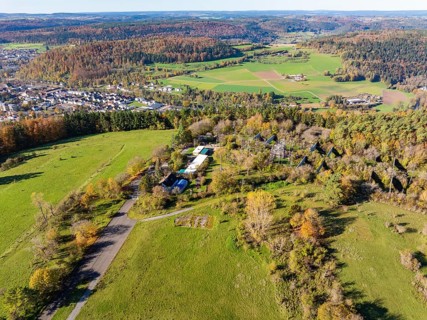 Wide landscape with fields, forests and a small village surrounded by autumnal trees, high ropes