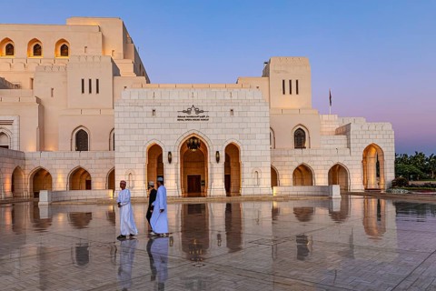 Local men walk across the main square in front of the Royal Opera at the blue hour, Muscat, Arabian