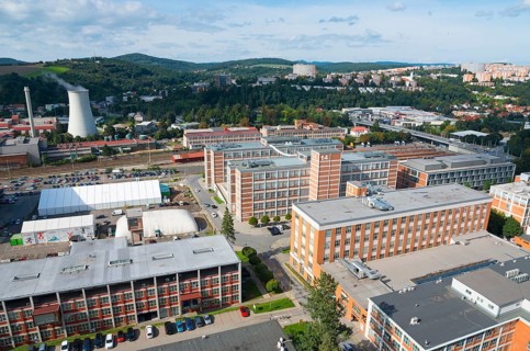 Spacious industrial area with multi-storey factory buildings surrounded by hills and urban