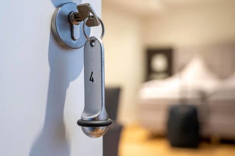 Symbolic image of a hotel, key inserted in the door of a hotel room, analogue lock