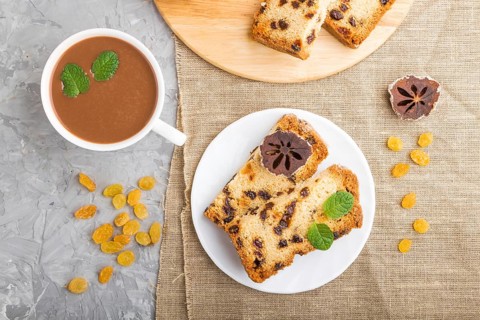Homemade cake with raisins, dried persimmon and a cup of hot chocolate on a gray concrete