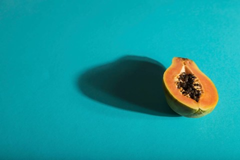 Ripe cut papaya on blue pastel background. Side view, copy space, hard light. Tropical, healthy
