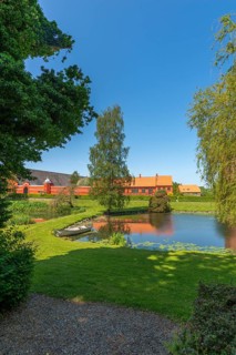 Farm building of Hesselagergaard Manor with park, lake, rowing boat, Fyn, Fyn Island, Denmark,