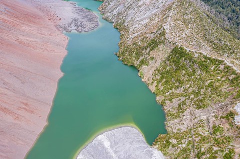 Dead trees, crater rim of Chaiten volcano, colored rock, small lake, aerial view, Park Pumalin,