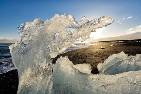 Backlit block of ice, beach at glacier lagoon Jökulsarlon, Breiðamerkursandur, south coast,