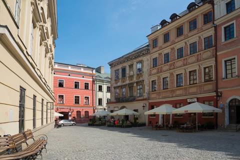 Cobbled old town alleyway with historic buildings and sunlight, benches at the roadside, Old Town