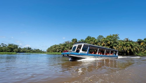 Tourists on a boat, Rio Suerte river in the rainforest, dense vegetation, Tortuguero National Park,