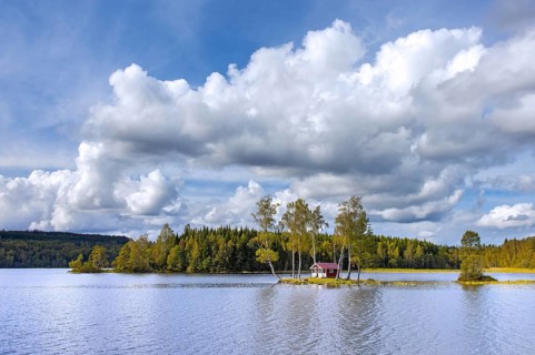 Small traditional red wooden cabin on tiny island in lake in autumn, fall, Värmland, west-central