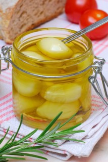 Garlictoes (Allium sativum) in olive oil, with rosemary