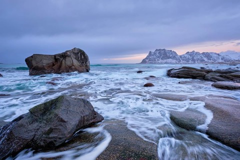 Rocks on beach of fjord of Norwegian sea in winteron sunset. Utakliev beach, Lofoten islands,