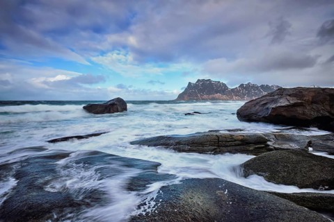 Rocks on beach of fjord of Norwegian sea in winter with snow. Utakliev beach, Lofoten islands,