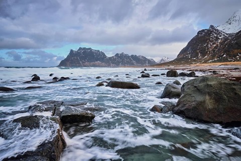 Rocks on beach of fjord of Norwegian sea in winter with snow. Utakliev beach, Lofoten islands,