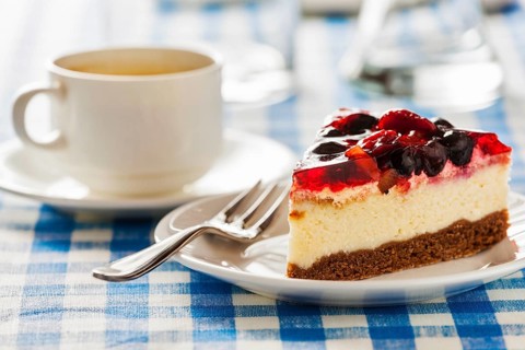 Dessert background, fruit cheese cake on plate with fork and coffee cup on blue checkered