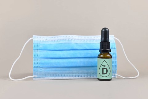 Medical face mask and bottle with vitamine drops on gray background