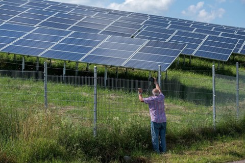Man photographing a fenced photovoltaic plant, Pfronten, Allgäu, Bavaria, Germany, Europe
