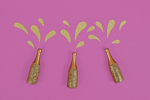 Three golden splashing Champagne bottles on purple background