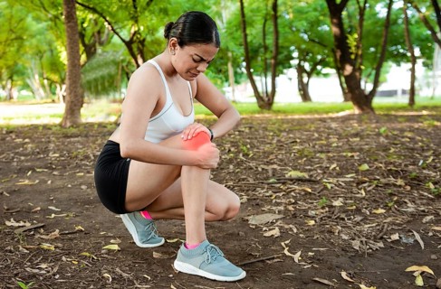 Athlete woman with knee muscle pain. Athlete girl on the ground with knee pain outdoors. Runner