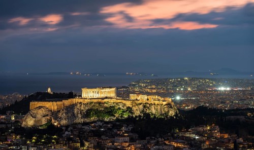 View over the sea of houses of Athens, illuminated Parthenon temple on the Acropolis, dramatic