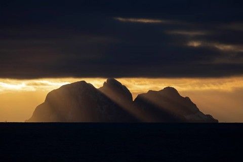 Island Værøy at the southern end of Lofoten under clouds with sunrays