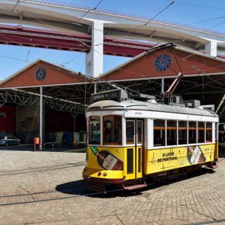 Historic yellow tram, Eléctrico, line 28 in front of tram depot and repair shop, Lisbon, Portugal,