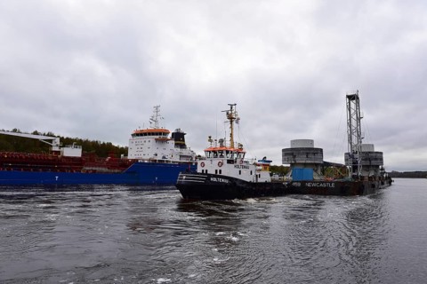 Tugboat towing a pontoon with offshore installation in the Kiel Canal, Schleswig-Holstein, Germany,