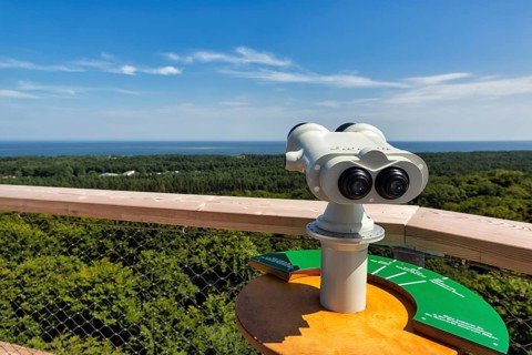 White telescope on viewing platform points towards the Baltic Sea, treetop path at the Rügen