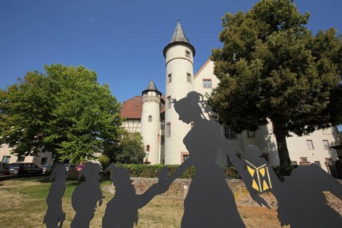 Figures from the fairy tale Snow White and the Seven Dwarfs in front of the late Gothic castle