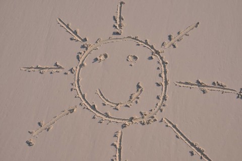 Sun face drawn in the sand