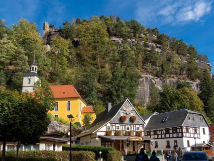 Half-timbered houses and small village church on a slope, half-timbered houses in front of rocks,