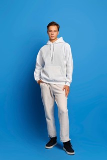 Attractive stylish man wearing white sweatshirt and sweatpants standing over blue studio background