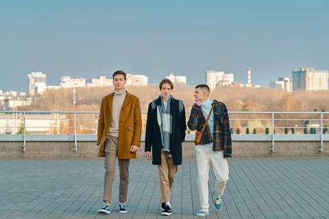 Three young men in autumn clothes are walking down the street