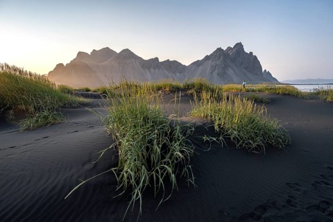 Tourist on a sand dune, Black beach with volcanic sand, Sand beach, Dunes with grass, Stokksnes