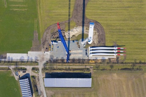Aerial view over construction site showing rotor blades on the ground and building crane assembling